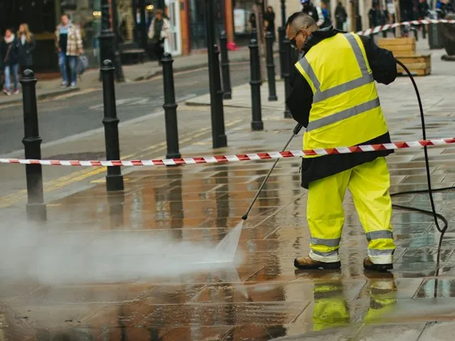 a worker pressure washing pavement