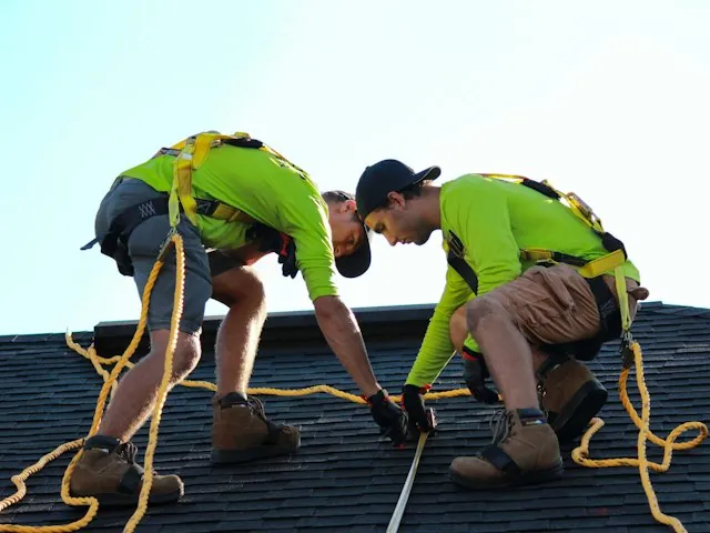 two roofers working on a shingle roof