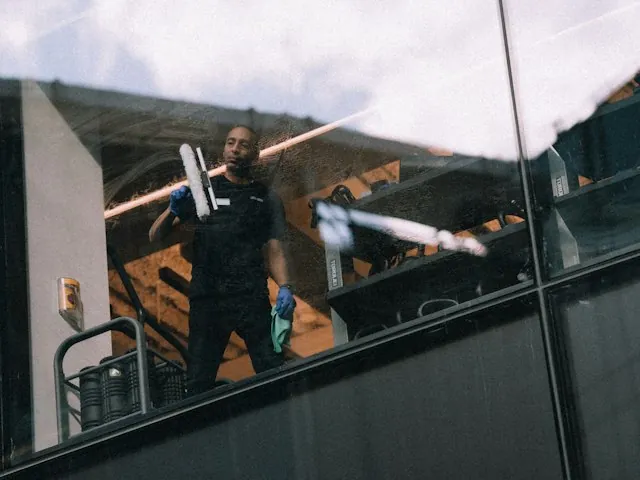 a professional window cleaner using a squeegee and scrubber on glass