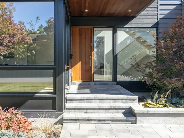a modern home entry with large windows and a wood front door